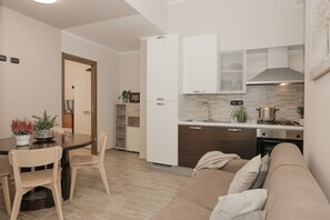 Eine moderne Küche mit weißen Schränken, einem eingebauten Ofen und einem Essbereich mit Tisch und Stühlen.
