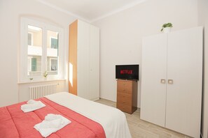 Ein Hotelzimmer mit Bett, Kleiderschrank, Fernseher und Fenster.