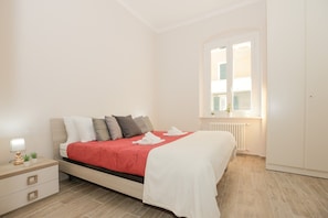 Una camera da letto con un letto, un comodino, una lampada e una finestra.