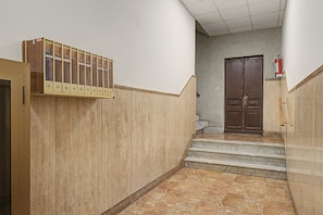 Un corridoio con un estintore fissato al muro, un insieme di porte doppie e un rilevatore di fumo sulla parete.