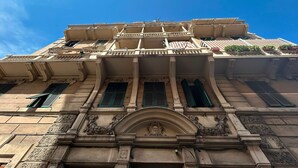 Un edificio histórico con detalles arquitectónicos ornamentados, que incluyen una entrada abovedada destacada y varios balcones.