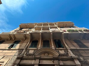 Ein historisches Gebäude mit aufwendigen architektonischen Details, darunter ein markanter Bogenportal und mehrere Balkone.