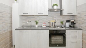 Une cuisine moderne avec des armoires blanches, un évier en acier inoxydable, une cuisinière et un four encastré.