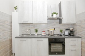 A modern kitchen with white cabinets, a stainless steel sink, a stove, and a built-in oven. - Maison Sirivle 7.2 Apartment with Private Terrace and Wi-Fi (Genoa)