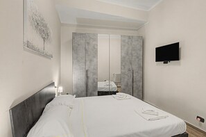 A hotel room with a bed, a flat-screen TV mounted on the wall, and a large mirror reflecting the room. - Maison Sirivle 7.2 Apartment with Private Terrace and Wi-Fi (Genoa)