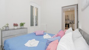 Une chambre à coucher avec un lit, des oreillers, une commode et un radiateur.