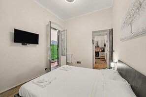 Een hotelkamer met een bed, een flatscreen televisie, een deur naar een balkon en een kitchenette.
