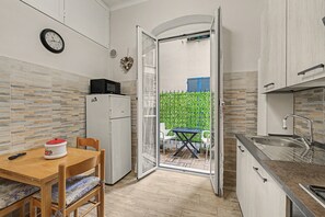 Een kleine keuken met een eethoek, een koelkast, een magnetron en een spoelbak.