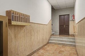 Een hal met een brandblusser aan de muur, een paar dubbele deuren en een rookmelder aan de muur.