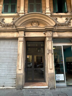 A building entrance with a closed shutter, a door with a glass panel, and a sign for a pet dry wash service. - Maison Sirivle 7.2 Apartment with Private Terrace and Wi-Fi (Genoa)