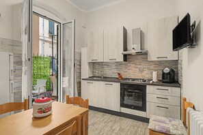 A modern kitchen with wooden cabinets, a gas stove, an oven, and a television mounted on the wall. - Maison Sirivle 7.2 Apartment with Private Terrace and Wi-Fi (Genoa)