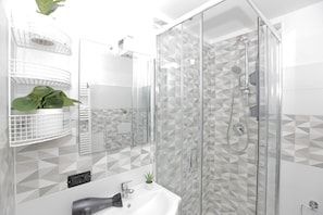 A modern bathroom with a glass shower enclosure, a white sink, and geometric patterned tiles. - Maison Sirivle 7.2 Apartment with Private Terrace and Wi-Fi (Genoa)