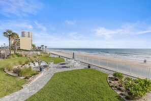 A coastal hotel with a paved walkway, outdoor seating, and a view of the beach and ocean. - 🌴Panoramic Ocean + River Views 19th Floor Corner Condo - Towers Ten 1901 (Daytona Beach Shores)