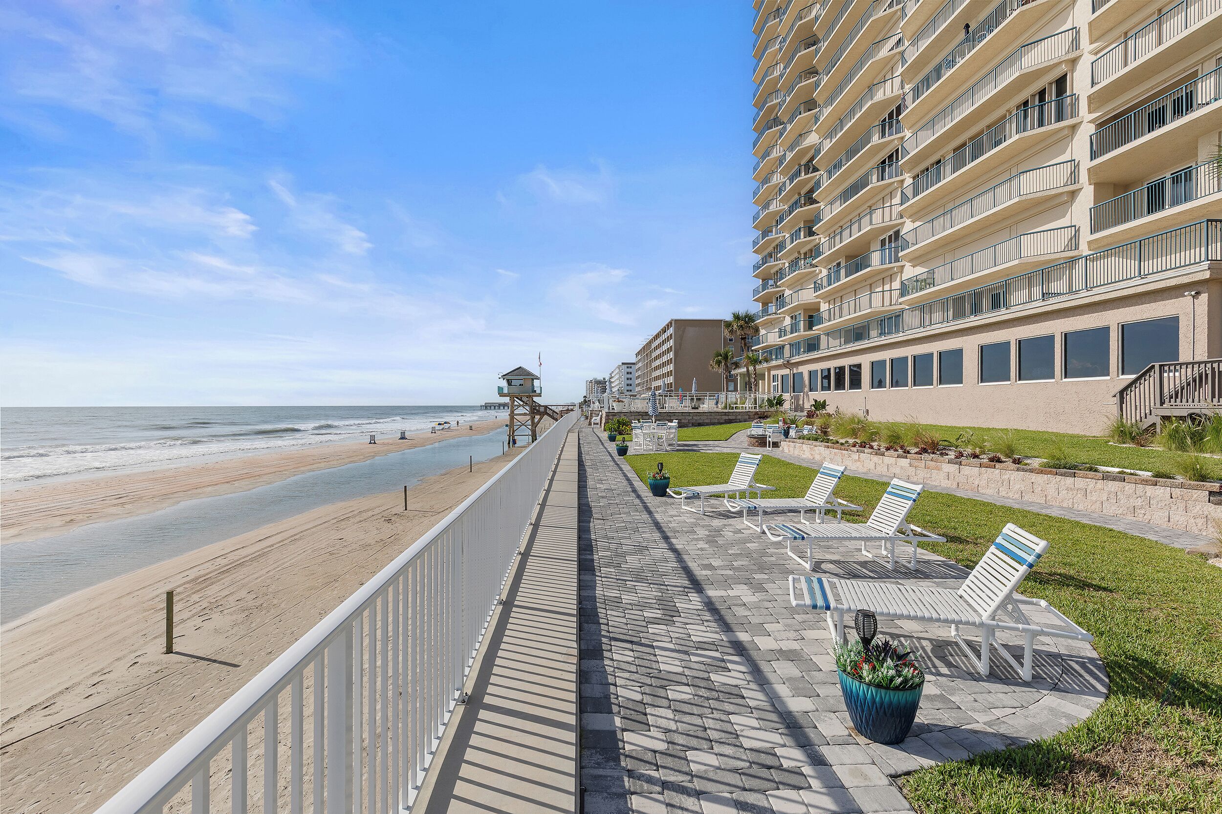A beachfront hotel with a boardwalk, beach access, and outdoor seating areas.