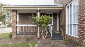 Un edificio residenziale con facciata in mattoni, un portico coperto e un piccolo giardino con un vialetto che conduce all'ingresso.