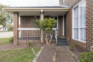 A residential building with a brick exterior, a covered porch, and a small garden area with a pathway leading to the entrance. - Havana Edge Pet friendly Garden Retreat near Beach (Frankston)