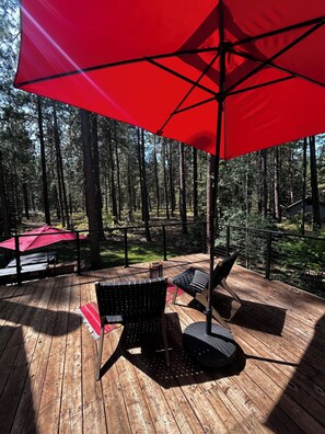 A wooden deck with outdoor furniture and a red umbrella.
