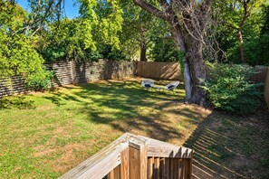 Ein Garten mit Holzzaun, einem Baum und zwei weißen Stühlen.