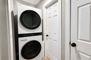 A laundry room with two stacked washing machines and a door. - Pet-Friendly 4BR Duplex + Fire Pit (Raleigh)