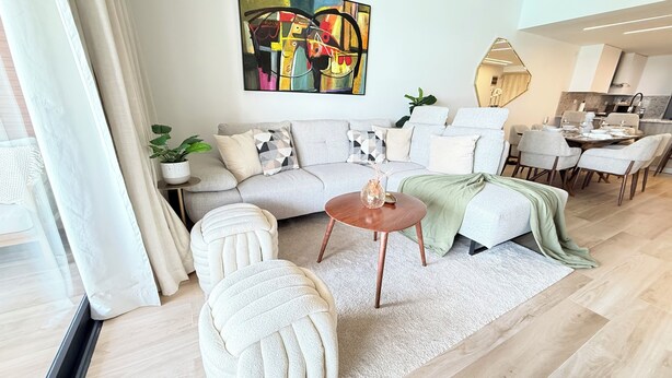 A modern living room with a sofa, armchairs, a coffee table, and a dining area with chairs and a table. - Sky Lagoon Retreat, 2BR The City Place, Punta Cana (Punta Cana)