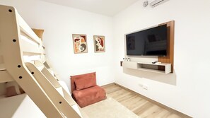 Ein modernes Wohnzimmer mit Treppe, einem flachbildfernseher an der Wand und zwei abstrakten Wandbildern.