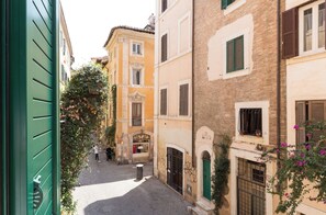 Une rue étroite, bordée de bâtiments des deux côtés, qui présente un mélange de styles architecturaux et dont le sol est pavé.