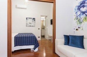 Una camera da letto con un letto, un divano bianco, un quadro e una porta che conduce al bagno.