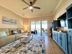 A living room with a sofa, coffee table, and a ceiling fan. - Seascape 3BR Condo w/ Hammock Beach Resort Access (Palm Coast)