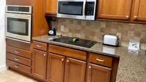 Eine Küche mit Holzschränken, einer Mikrowelle, einem Backofen, einem Toaster und einem Mixer.