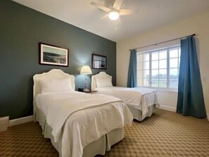 A hotel room with two beds, a ceiling fan, and a window with curtains. - Charming 2BR Condo w/ Hammock Beach Resort Access (Palm Coast)