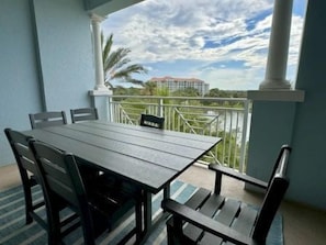 A balcony with a table and chairs, overlooking a cityscape. - Harborview 2BR Condo | Hammock Beach Resort Access (Palm Coast)