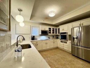 Una cocina con armarios blancos, electrodomésticos de acero inoxidable y encimera de mármol.