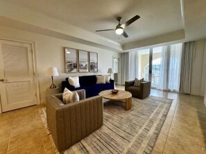 A spacious living room with a sofa set, a coffee table, and a ceiling fan. - Modern 3BR Condo w/ Hammock Beach Resort Access (Palm Coast)