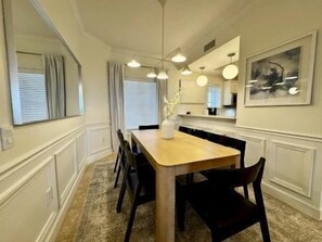 A dining area with a wooden table, black chairs, pendant lights, and a vase on the table. - Modern 3BR Condo w/ Hammock Beach Resort Access (Palm Coast)