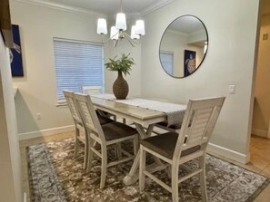 A dining area with a table, chairs, a chandelier, a mirror, and a potted plant. - Waterway-View 3BR Condo w/ Marina + Resort Access (Palm Coast)
