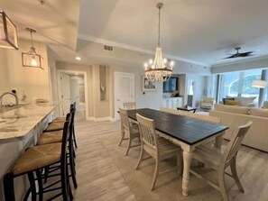 A dining area with a large table and chairs, a chandelier, and a view of the outdoors. - 2BR Waterview Condo | Marina, Pool & Resort Access (Palm Coast)