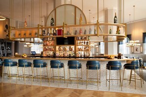 A bar area with a curved counter, multiple shelves of bottles, and blue bar stools. - 2BR Waterview Condo | Marina, Pool & Resort Access (Palm Coast)