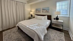 Een slaapkamer met een bed, nachtkastjes, een plafondventilator en een raam met jaloezieën.