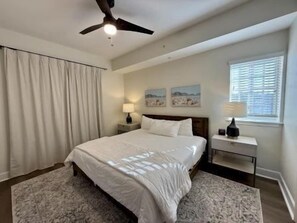 A bedroom with a bed, nightstands, a ceiling fan, and a window with blinds. - Bright Waterfront 3BR Condo | Pool & Resort Access (Palm Coast)