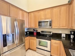 A kitchen with wooden cabinets, stainless steel appliances, a microwave, and a stove. - Golf View 3BR Condo w/ Hammock Beach Resort Access (Palm Coast)