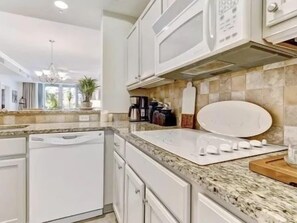 A kitchen with white cabinets, a granite countertop, and a built-in oven. - Pool-View 2BR Condo w/ Hammock Beach Resort Access (Palm Coast)
