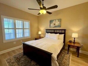 A bedroom with a bed, two bedside tables, a ceiling fan, and a window with blinds. - 2BR Condo w/ Marina + Hammock Beach Resort Access (Palm Coast)