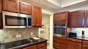 Une cuisine avec des meubles en bois, un four à micro-ondes en acier inoxydable et un four double.