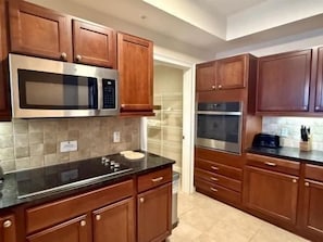 A kitchen with wooden cabinets, a stainless steel microwave, and a double oven. - Waterway 2BR Condo | Marina, Pool + Resort Access (Palm Coast)