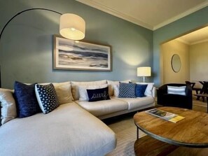 A modern living room with a sofa, coffee table, and a painting on the wall. - Horizon-View Condo w/ Hammock Beach Resort Access (Palm Coast)