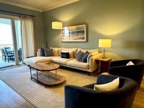 Ein Wohnzimmer mit einer Couch, Sesseln, einem Couchtisch und einer Lampe.
