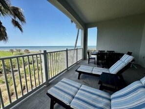 A balcony with a view of the ocean, a seating area with striped cushions, and a table. - Ocean View Condo w/ Balcony, Pools & Resort Access (Palm Coast)