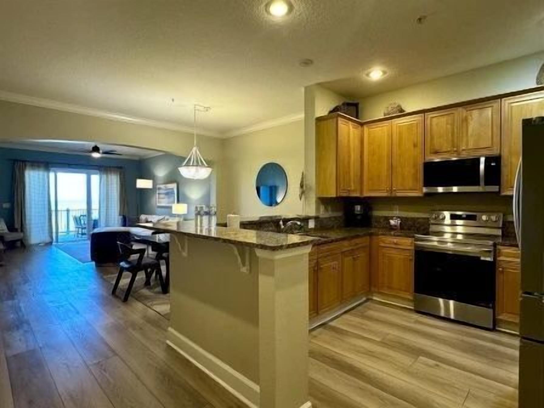 A modern kitchen with a central island, stainless steel appliances, and wooden cabinets.