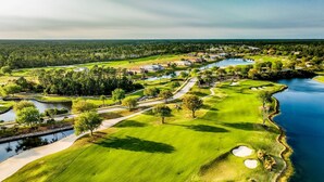 A golf course with bunkers, water hazards, and a clubhouse. - Serene 2BR Water-View Condo | Pool & Resort Access (Palm Coast)