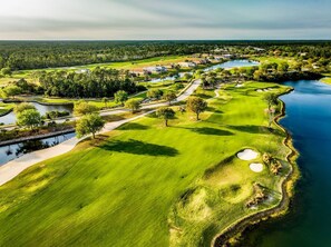A golf course with bunkers, water hazards, and a clubhouse. - Serene 2BR Water-View Condo | Pool & Resort Access (Palm Coast)